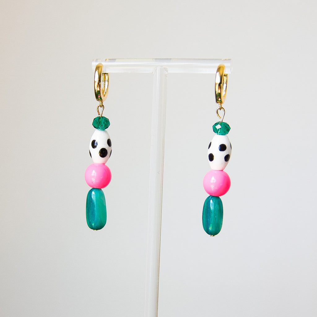 Colorful beaded earrings on a clear stand against a white background