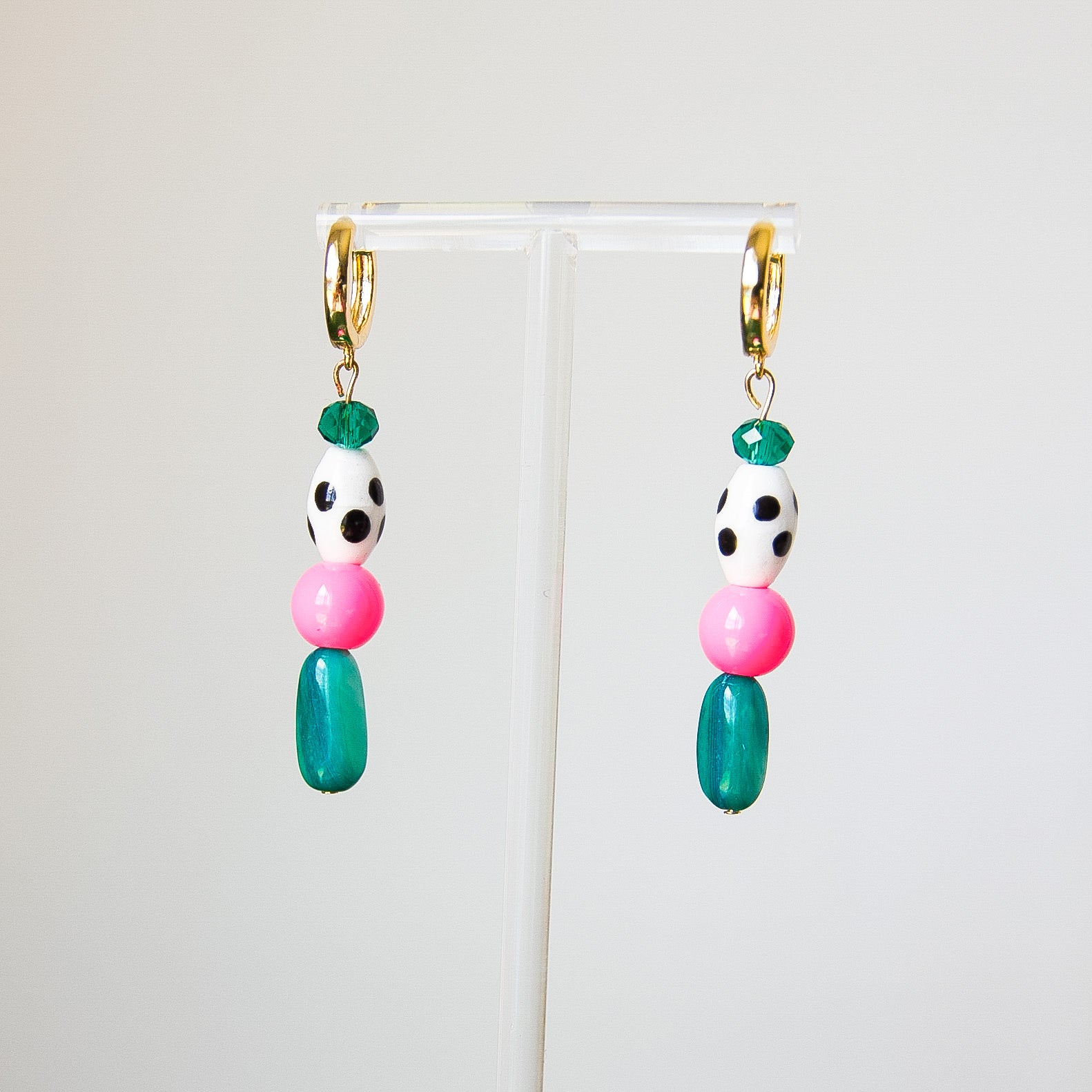 Colorful beaded earrings on a clear stand against a white background
